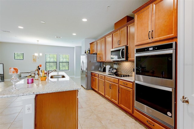 kitchen featuring brown cabinetry, tasteful backsplash, stainless steel appliances, and a sink