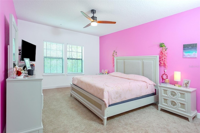 bedroom with light carpet, a textured ceiling, a ceiling fan, and baseboards