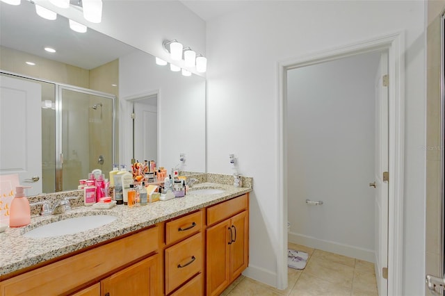 bathroom with double vanity, a stall shower, a sink, and tile patterned floors