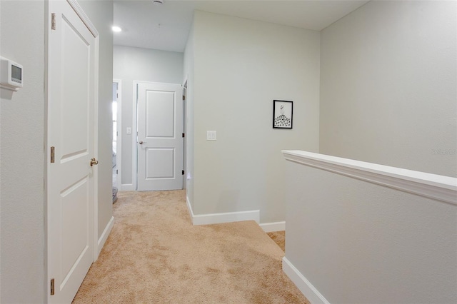 hallway with baseboards, an upstairs landing, and light colored carpet