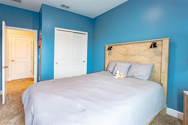 bedroom with baseboards, visible vents, a textured ceiling, carpet flooring, and a closet