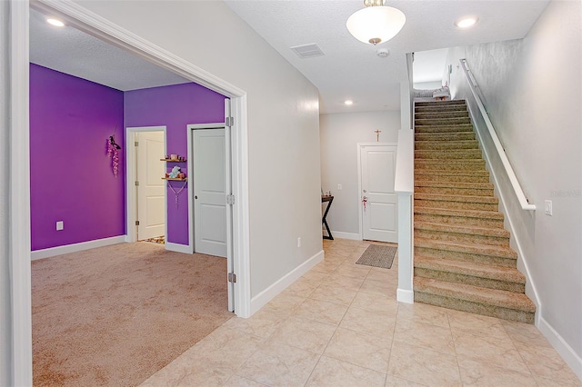 stairs with visible vents, carpet flooring, a textured ceiling, and baseboards