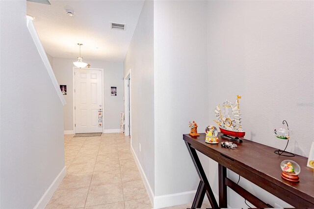 hallway featuring light tile patterned flooring, visible vents, and baseboards