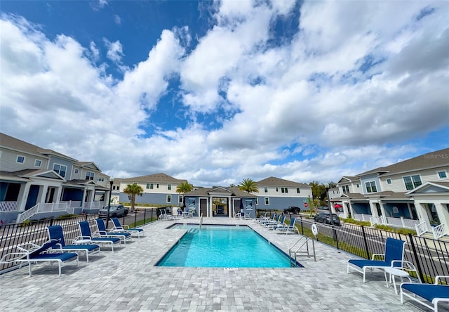 pool with a residential view, fence, and a patio