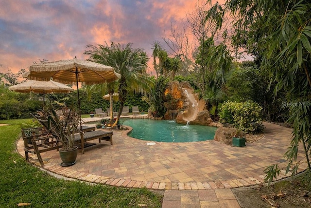 pool at dusk featuring an outdoor pool, a patio, and a water slide