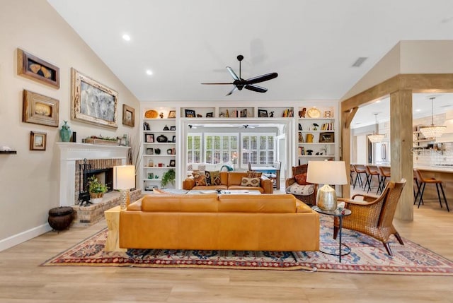 living area featuring a brick fireplace, wood finished floors, built in shelves, and vaulted ceiling