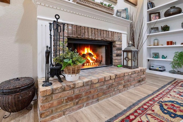 interior details with built in features, a fireplace, a textured wall, and wood finished floors