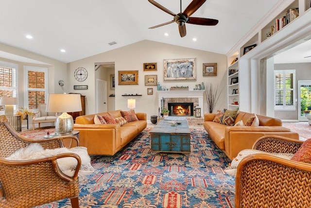 living room with visible vents, built in shelves, a brick fireplace, ceiling fan, and vaulted ceiling