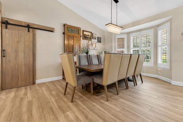 dining room with lofted ceiling, light wood-style flooring, a barn door, and baseboards