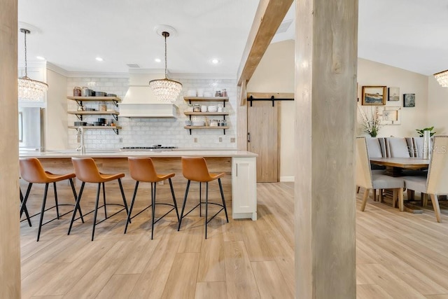 kitchen featuring open shelves, a barn door, stainless steel gas cooktop, and premium range hood