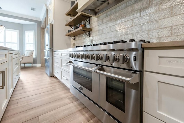 kitchen featuring stainless steel appliances, tasteful backsplash, white cabinets, and light wood finished floors