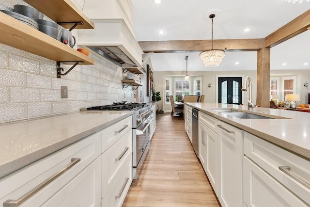 kitchen featuring open shelves, a sink, decorative backsplash, light countertops, and stainless steel appliances