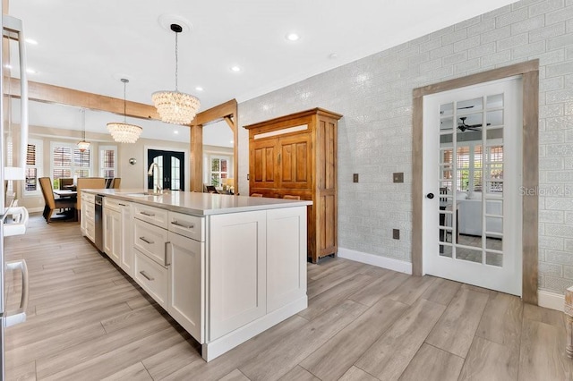 kitchen featuring light countertops, light wood-type flooring, french doors, white cabinets, and a kitchen island with sink