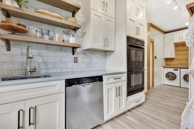 kitchen with washing machine and clothes dryer, open shelves, a sink, dobule oven black, and dishwasher