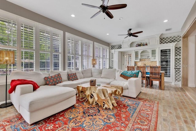 living area with brick floor, visible vents, a ceiling fan, and recessed lighting