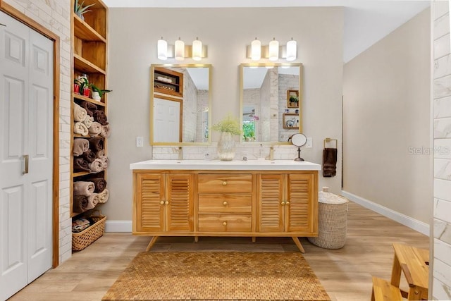 bathroom featuring double vanity, a sink, baseboards, and wood finished floors