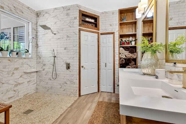 bathroom featuring a closet, tiled shower, vanity, and wood finished floors