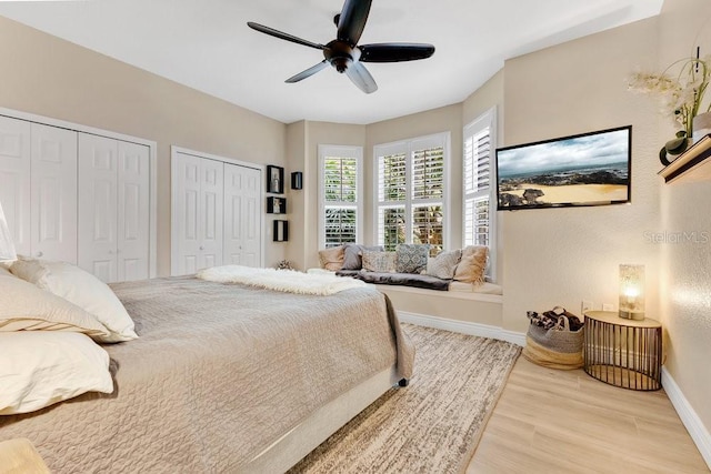 bedroom featuring ceiling fan, baseboards, two closets, and wood finished floors