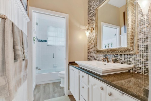 bathroom with vanity, wood finished floors,  shower combination, toilet, and backsplash