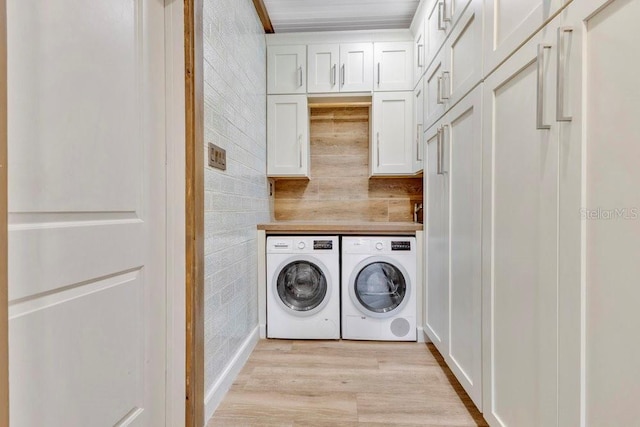 washroom with washing machine and clothes dryer, cabinet space, and light wood finished floors