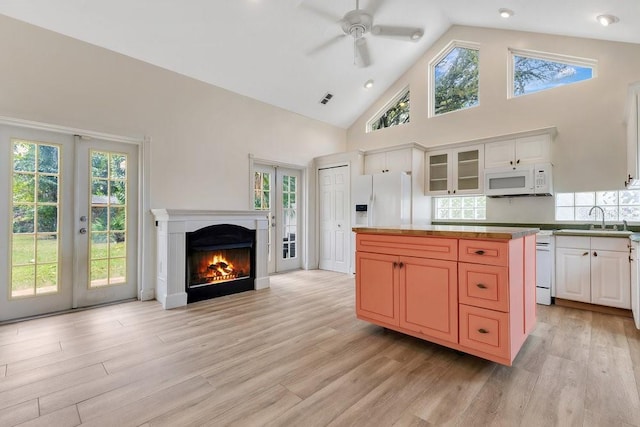 kitchen featuring light wood finished floors, a sink, french doors, and white appliances