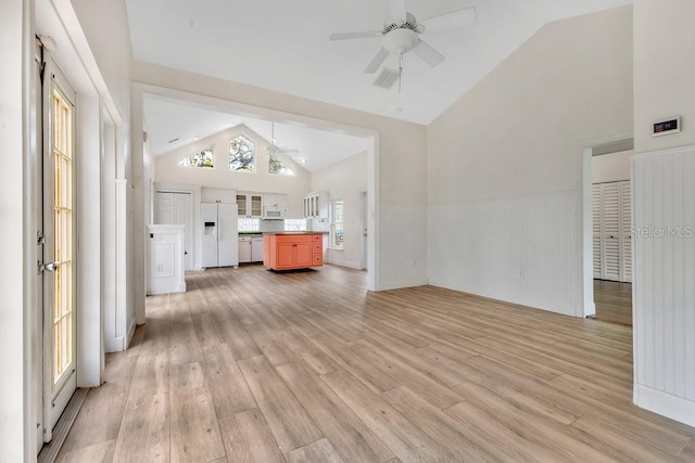 unfurnished living room with ceiling fan, light wood-type flooring, visible vents, and a wainscoted wall