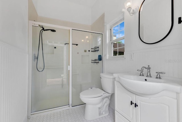 full bath featuring vanity, a shower stall, toilet, and a wainscoted wall