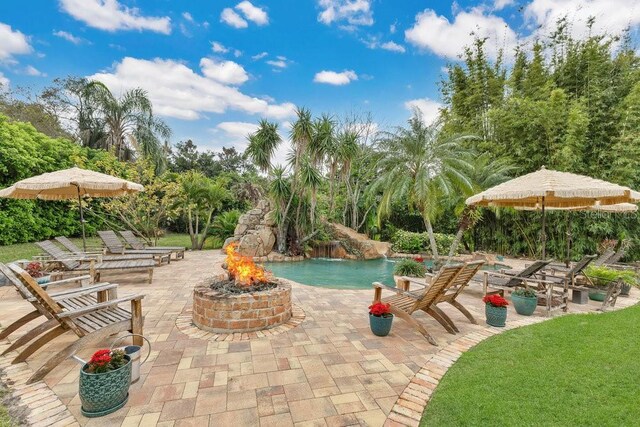 view of swimming pool featuring a patio and a fire pit