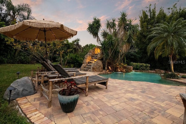 pool at dusk featuring a patio area and an outdoor pool