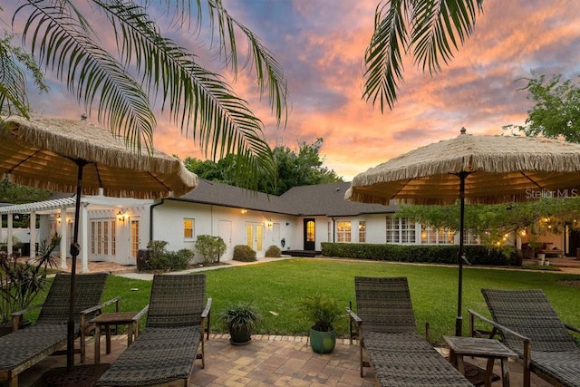 back of property featuring french doors, a yard, stucco siding, and a patio area