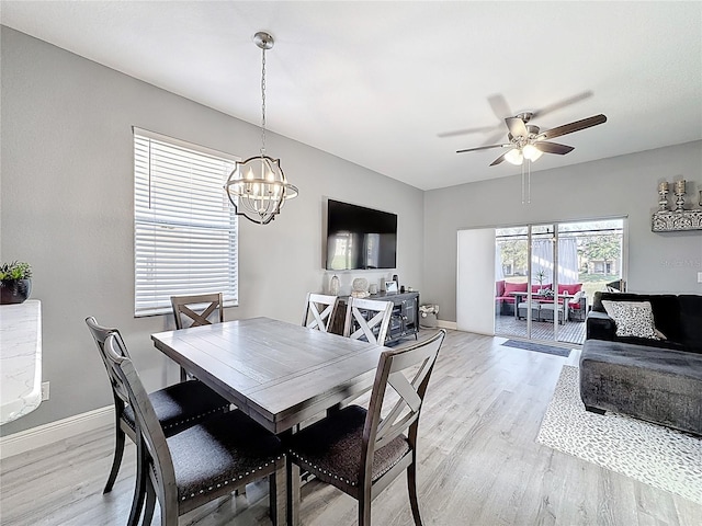 dining area with ceiling fan with notable chandelier, light wood-style flooring, and baseboards