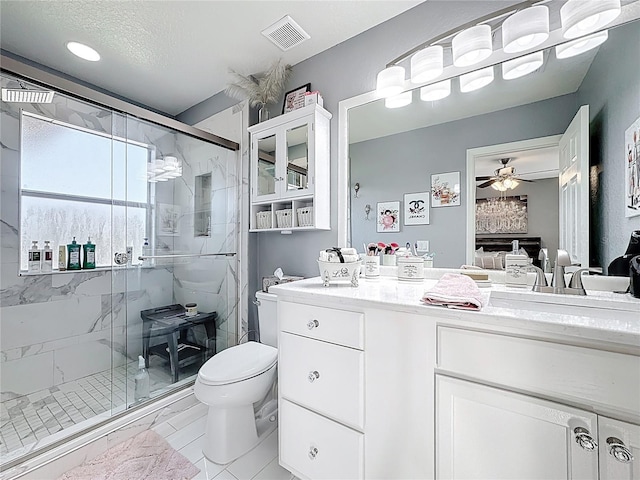 bathroom featuring visible vents, toilet, vanity, and a marble finish shower