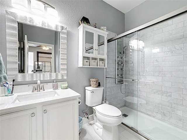 full bathroom with toilet, a stall shower, a textured wall, and vanity