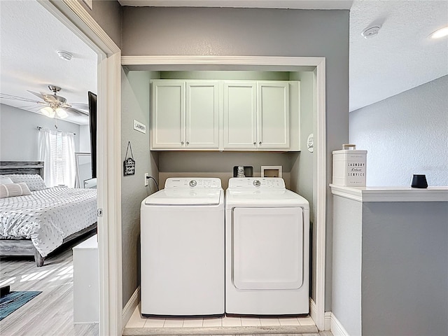 laundry area with cabinet space, light wood-style flooring, a ceiling fan, washing machine and dryer, and baseboards