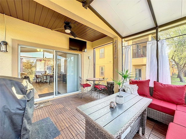 sunroom featuring a ceiling fan and vaulted ceiling with beams