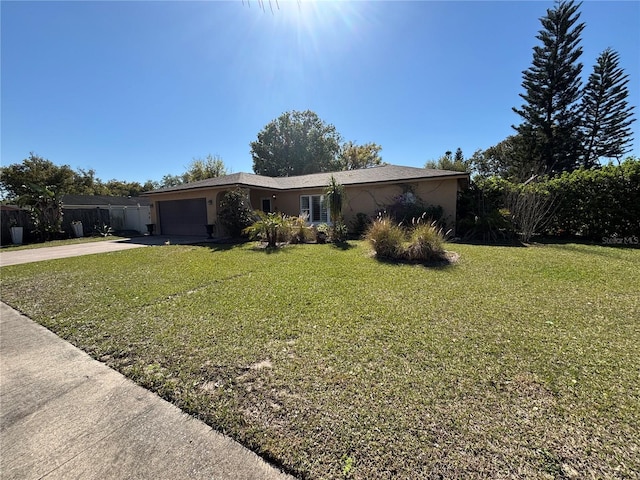 ranch-style house featuring a front lawn, an attached garage, driveway, and stucco siding