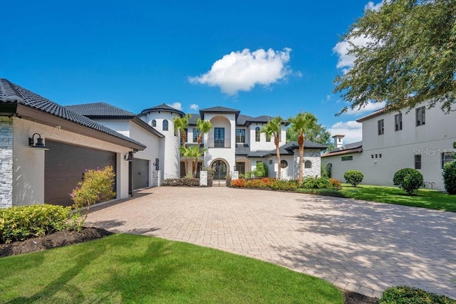 view of front of property with stucco siding, a front lawn, a garage, a tiled roof, and decorative driveway