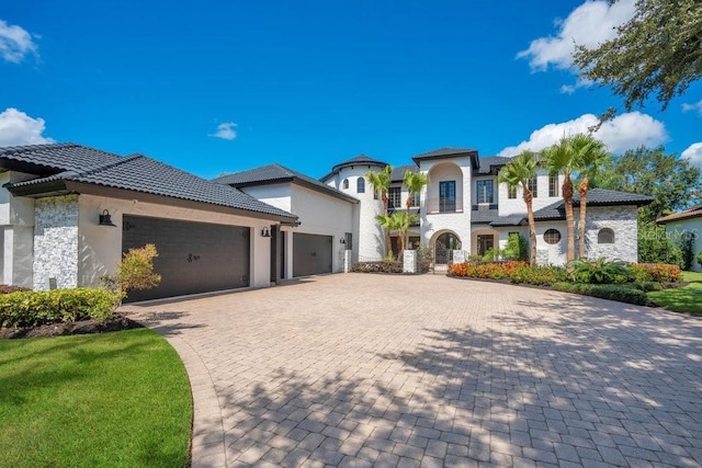 view of front of property featuring a tiled roof, decorative driveway, a garage, and stucco siding