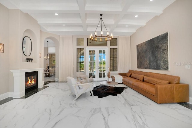 living room featuring french doors, marble finish floor, an inviting chandelier, and a glass covered fireplace