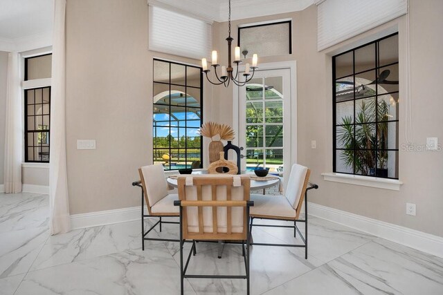 dining area with marble finish floor, an inviting chandelier, baseboards, and ornamental molding