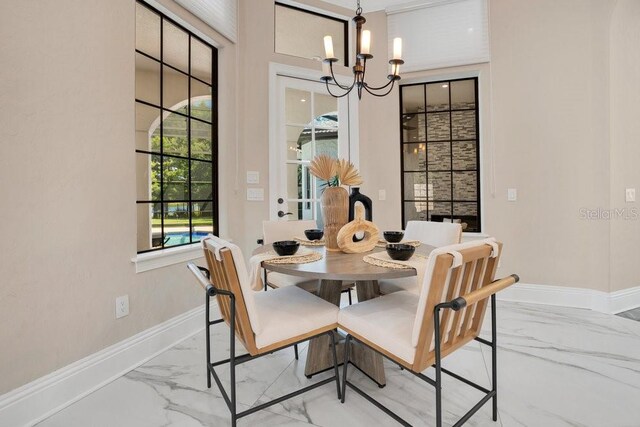 dining area featuring a chandelier, marble finish floor, and baseboards