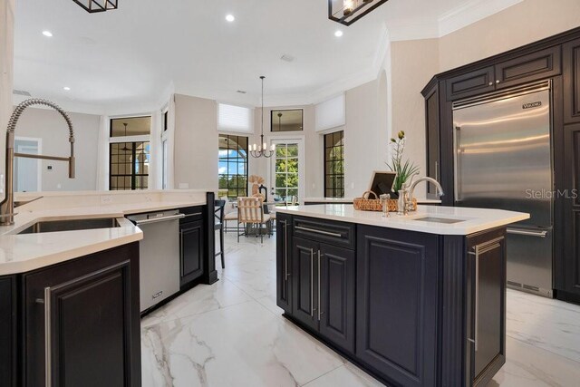 kitchen featuring a kitchen island with sink, light countertops, marble finish floor, stainless steel appliances, and a sink