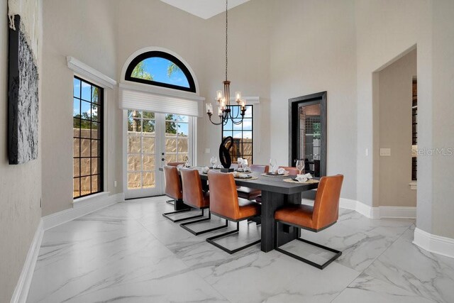 dining space with baseboards, a high ceiling, french doors, a notable chandelier, and marble finish floor