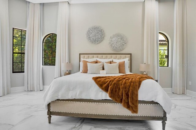 bedroom featuring marble finish floor and baseboards