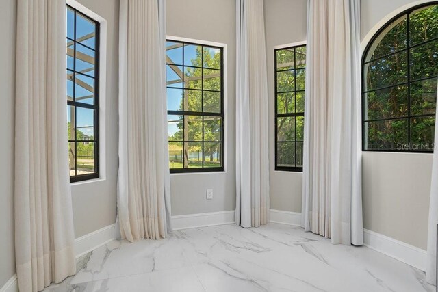 interior space featuring baseboards and marble finish floor