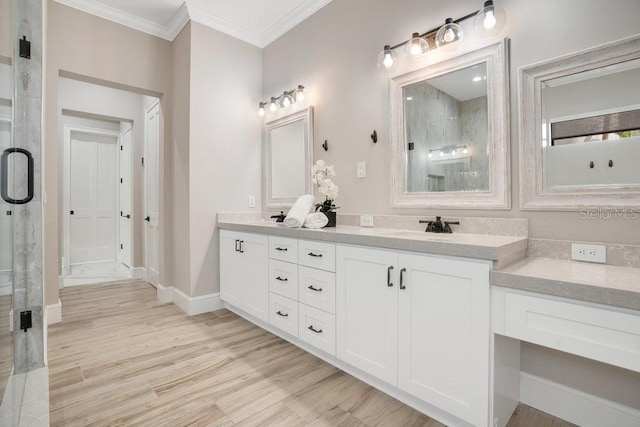 full bathroom featuring wood finished floors, baseboards, double vanity, crown molding, and a shower with door