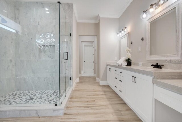 full bathroom featuring a shower stall, baseboards, ornamental molding, wood finished floors, and vanity