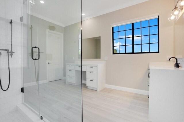 full bathroom with vanity, wood finished floors, baseboards, a stall shower, and crown molding