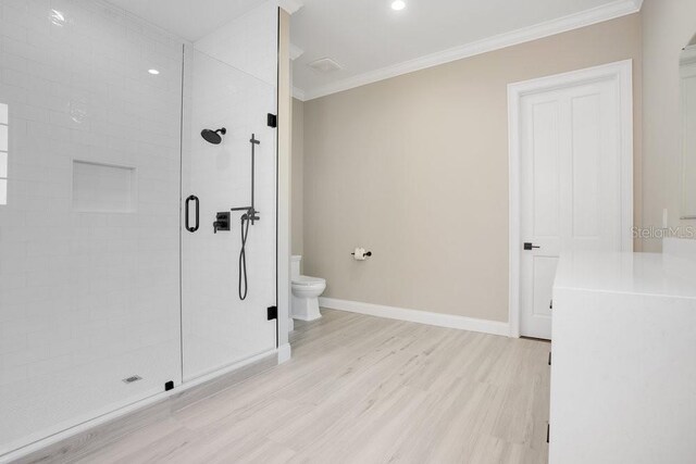 bathroom with wood finished floors, baseboards, ornamental molding, a shower stall, and toilet