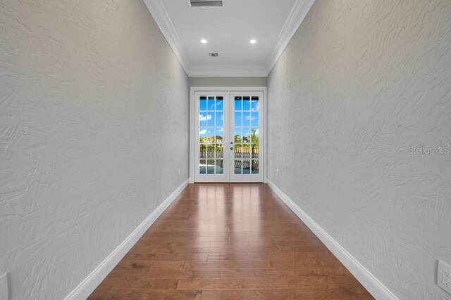 hallway with crown molding, wood finished floors, a textured wall, and french doors